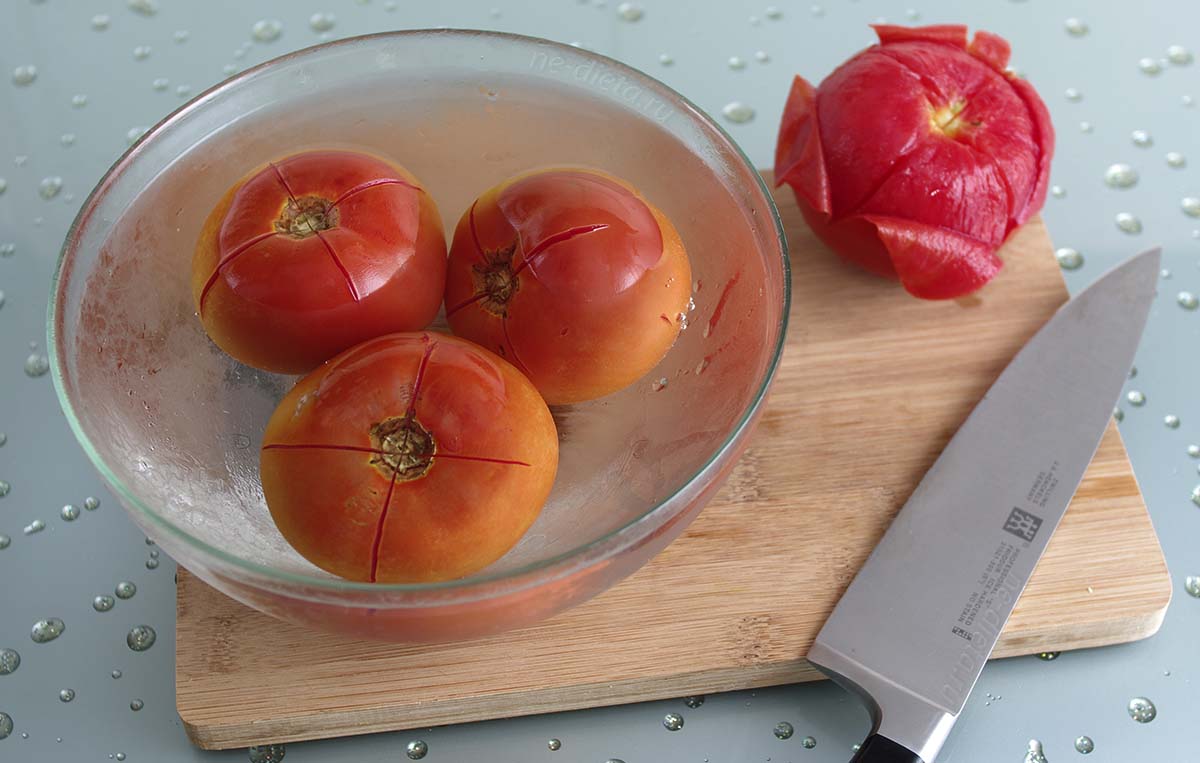 Ошпарить помидоры кипятком и очистить их.