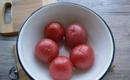 Вымойте помидоры, порежьте их крест-накрест и положите в миску.