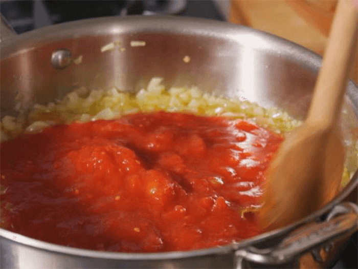 Добавьте томатную пасту к луку
